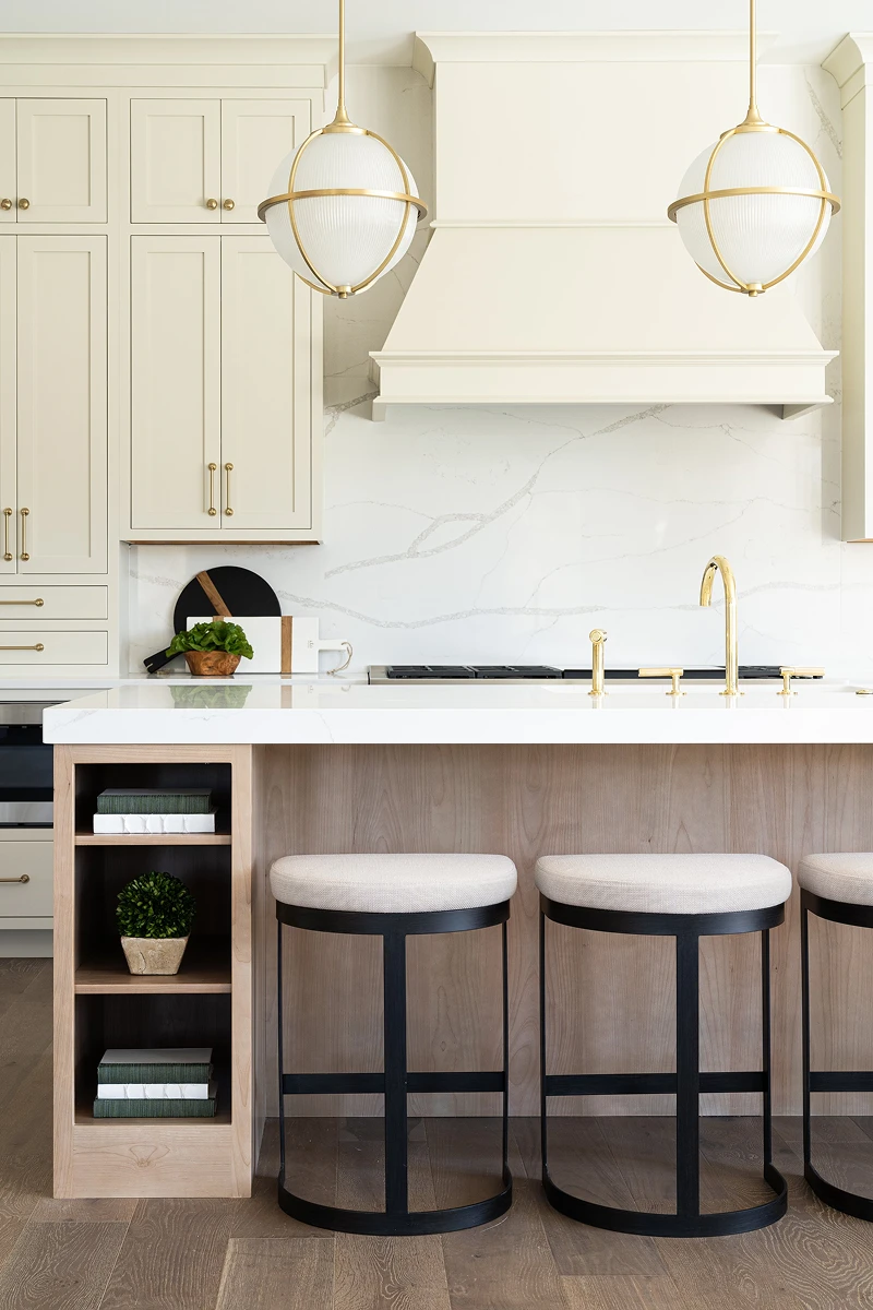 Custom cabinets in a custom kitchen with an island, gas stovetop, gold faucet.